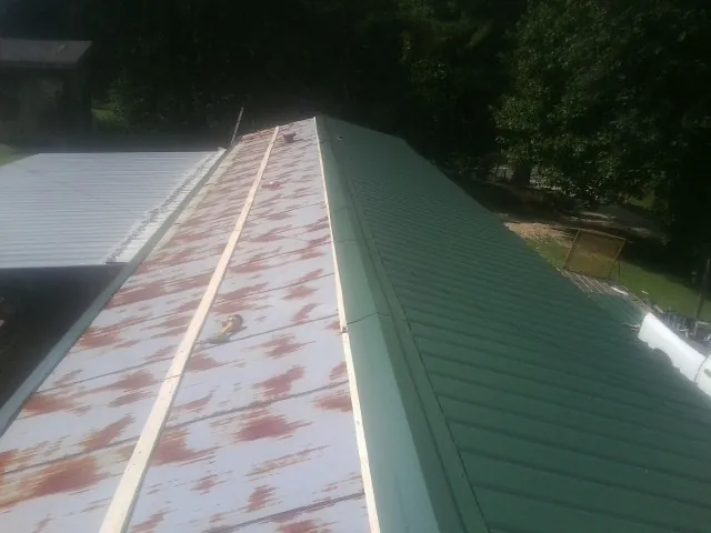 Old rusted panels beside newly installed green metal roofing — Wind Damage Roof Repair by Roofing Brothers in New Lexington