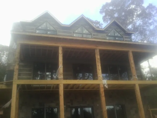 Dormers and porch framing on a large log home under construction — Roof Coating work by our crew in New Lexington