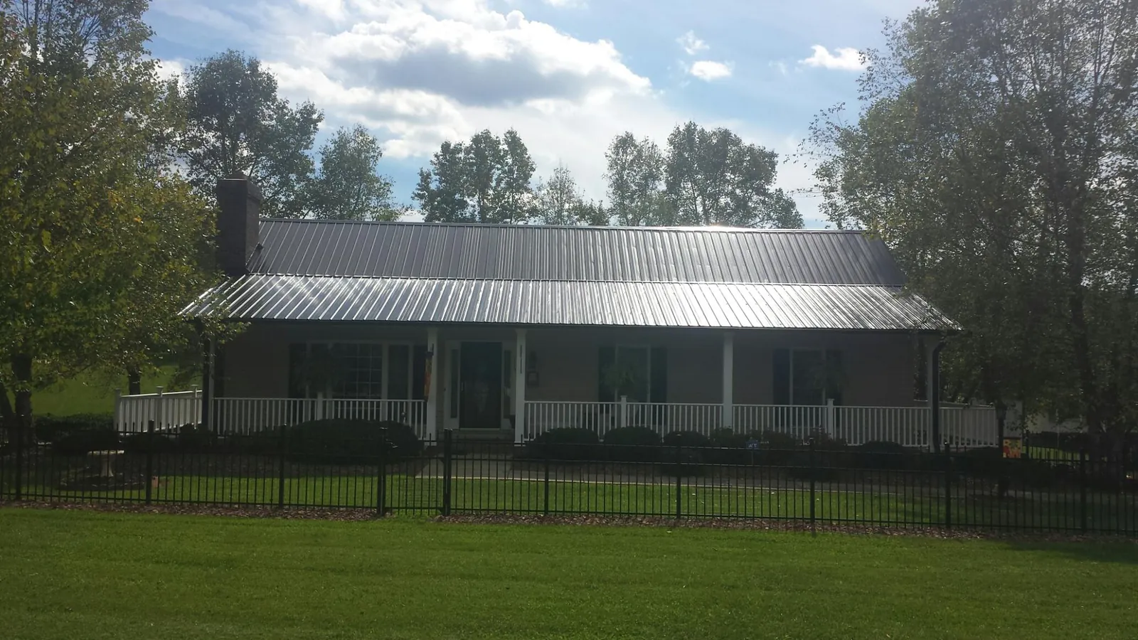 Gray metal roof on a brick ranch with a full width front porch — Gutter Guard Installation work by our crew in New Lexington