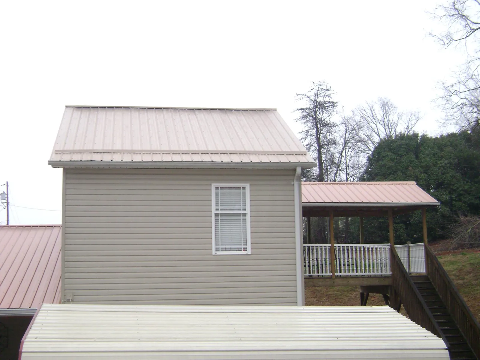 Tan metal roofs on a two story addition and attached porch, from a Roof Replacement job in New Lexington